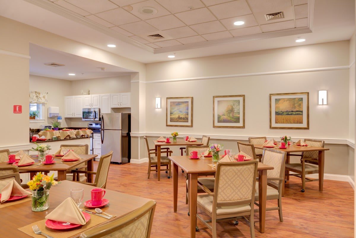 An inviting dining room with neatly arranged tables and chairs, featuring decorative artworks on the wall.