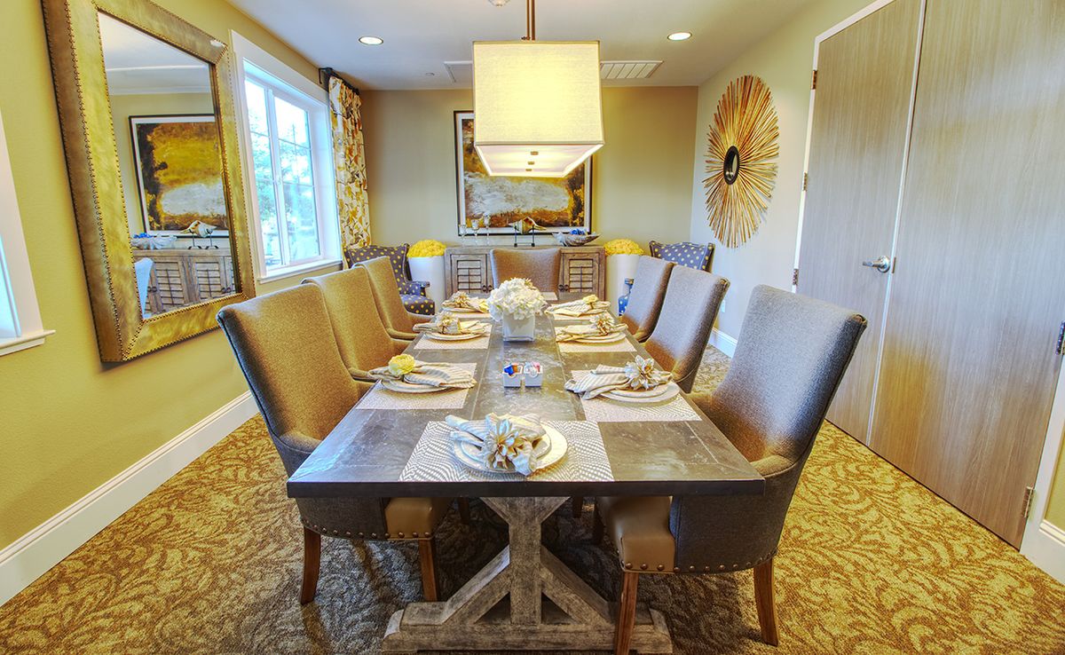 A warmly lit dining room with an elegantly set table and comfortable seating.