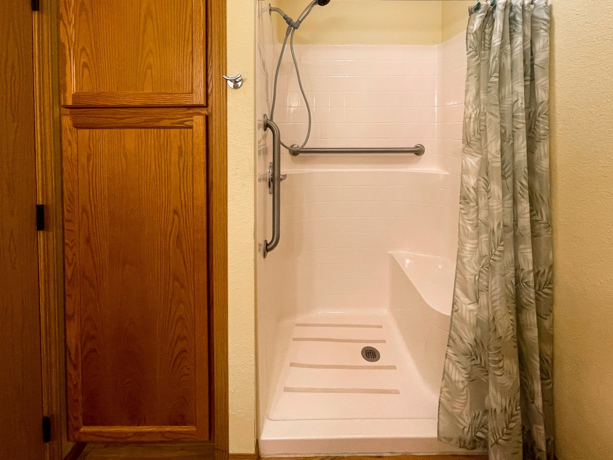 A bathroom shower with a grab bar and shower curtain.