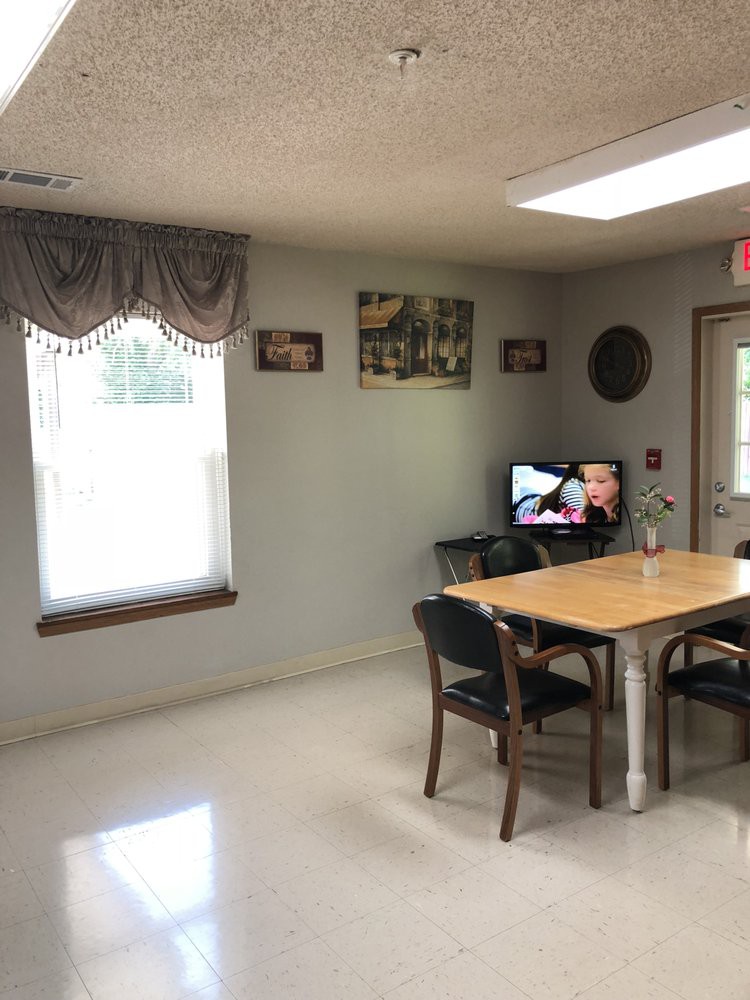A small room with a table and chairs, featuring a TV and wall decorations.