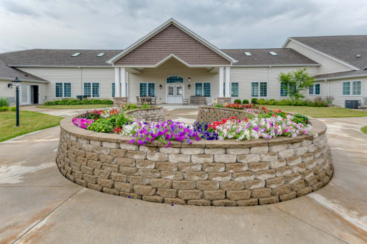 A well-maintained building entrance with a circular flower garden and stone wall.