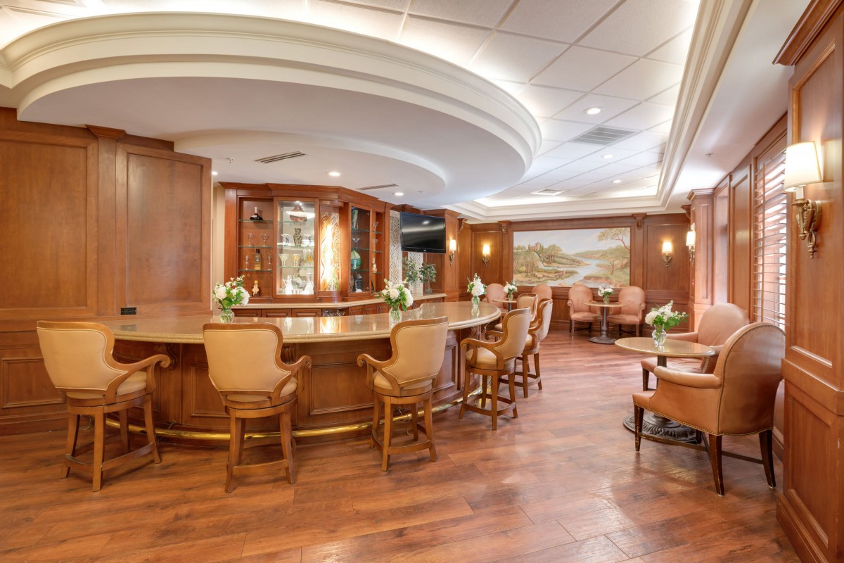 A well-lit and elegantly designed bar area with wooden furnishings and comfortable seating.