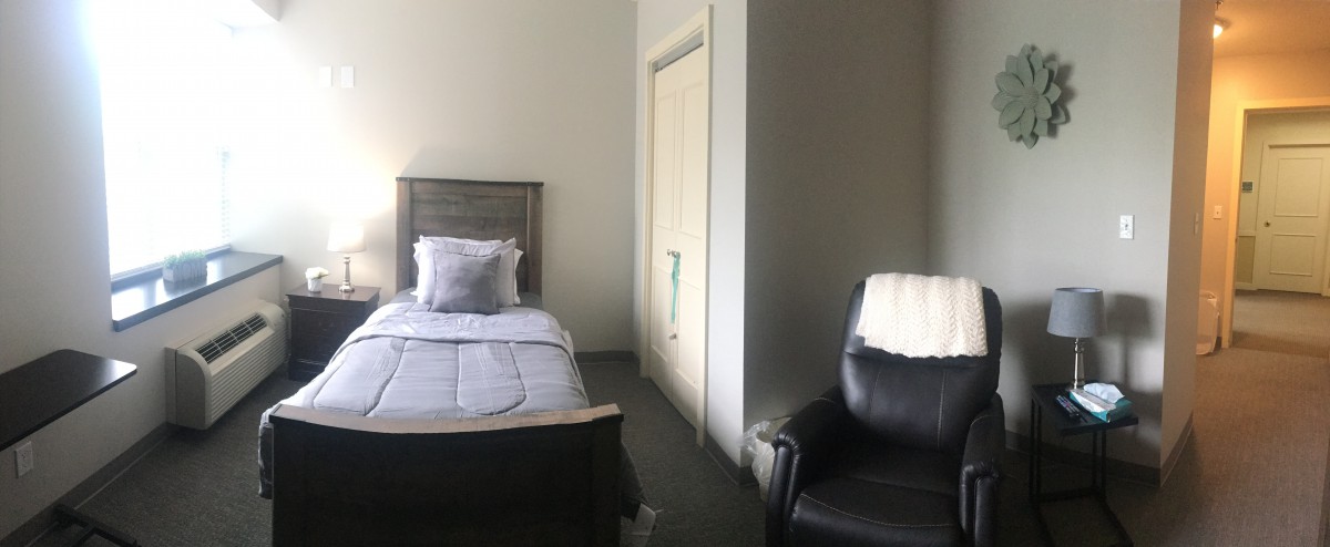 A minimalist bedroom featuring a single bed and a comfortable chair.