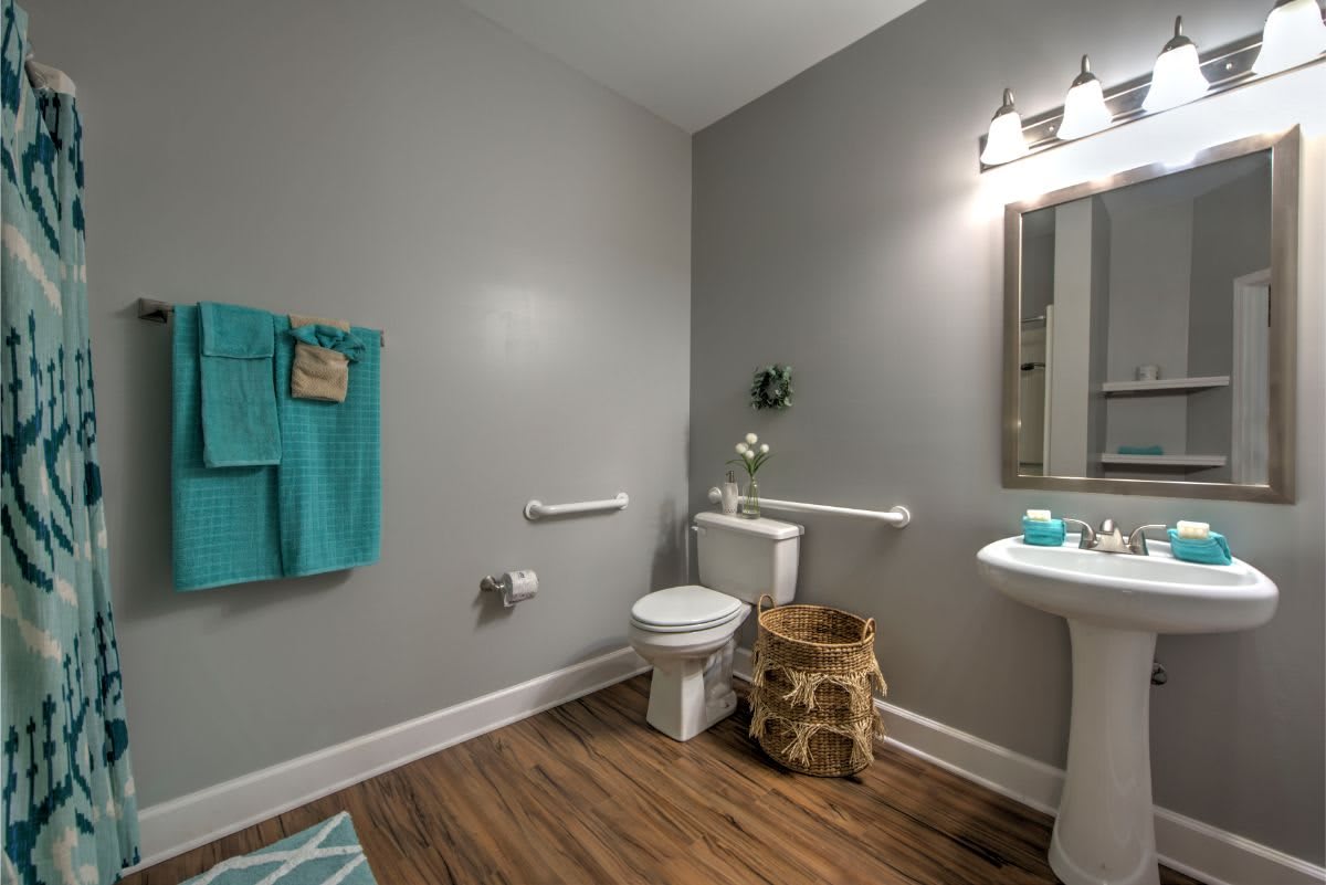Modern bathroom with a toilet, pedestal sink, and decorative elements.