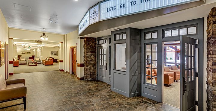 A quaint theater entrance inside a building with a marquee displaying 'LET'S GO TO THE...'.