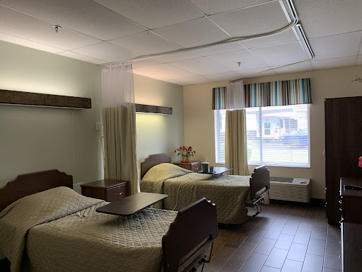 A shared hospital room featuring two patient beds and ample natural light from the window.
