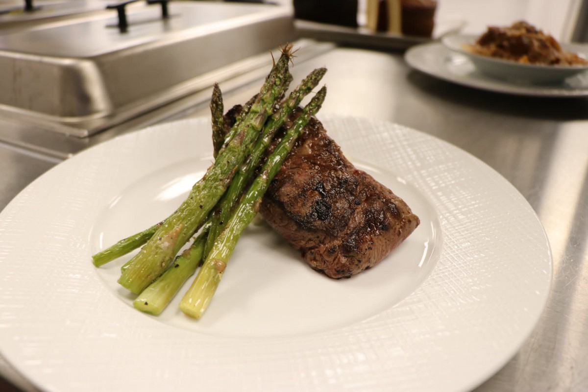 A deliciously plated steak with a side of grilled asparagus.