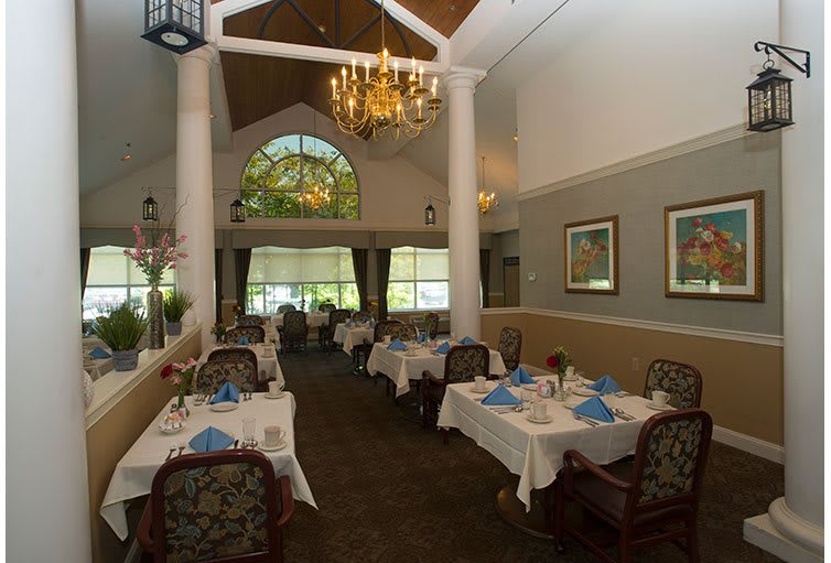 An elegant restaurant dining room with neatly set tables and a chandelier.