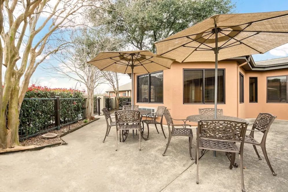 A sunny patio with outdoor tables and chairs shaded by large umbrellas.