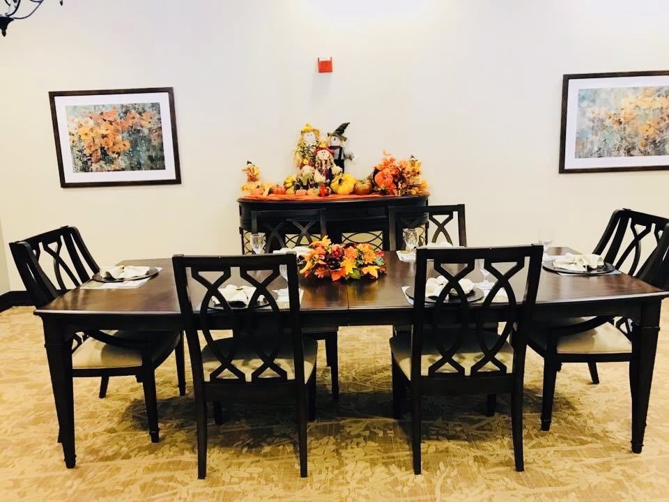 A dining room setup with a table and chairs, decorated with an autumn-themed centerpiece.