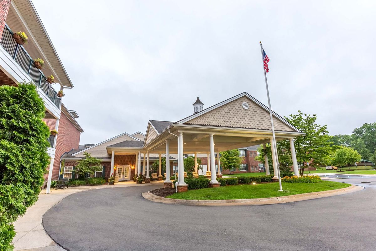 A building entrance with a covered driveway and a flagpole nearby.