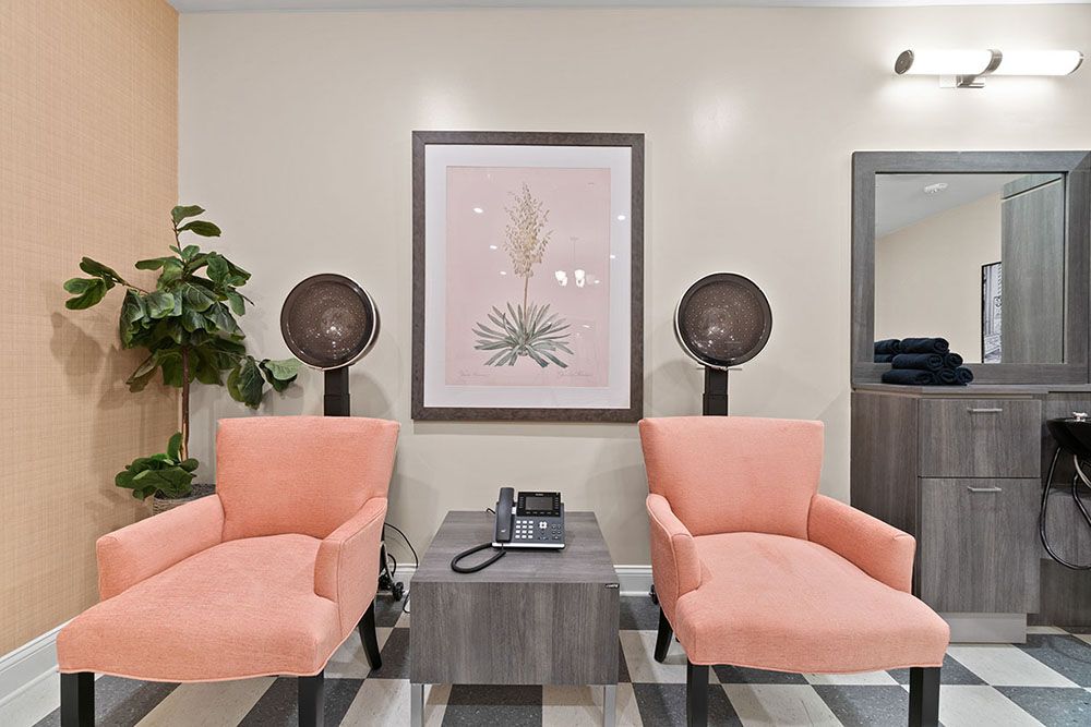 A cozy salon waiting area with pink chairs and vintage hair dryers.