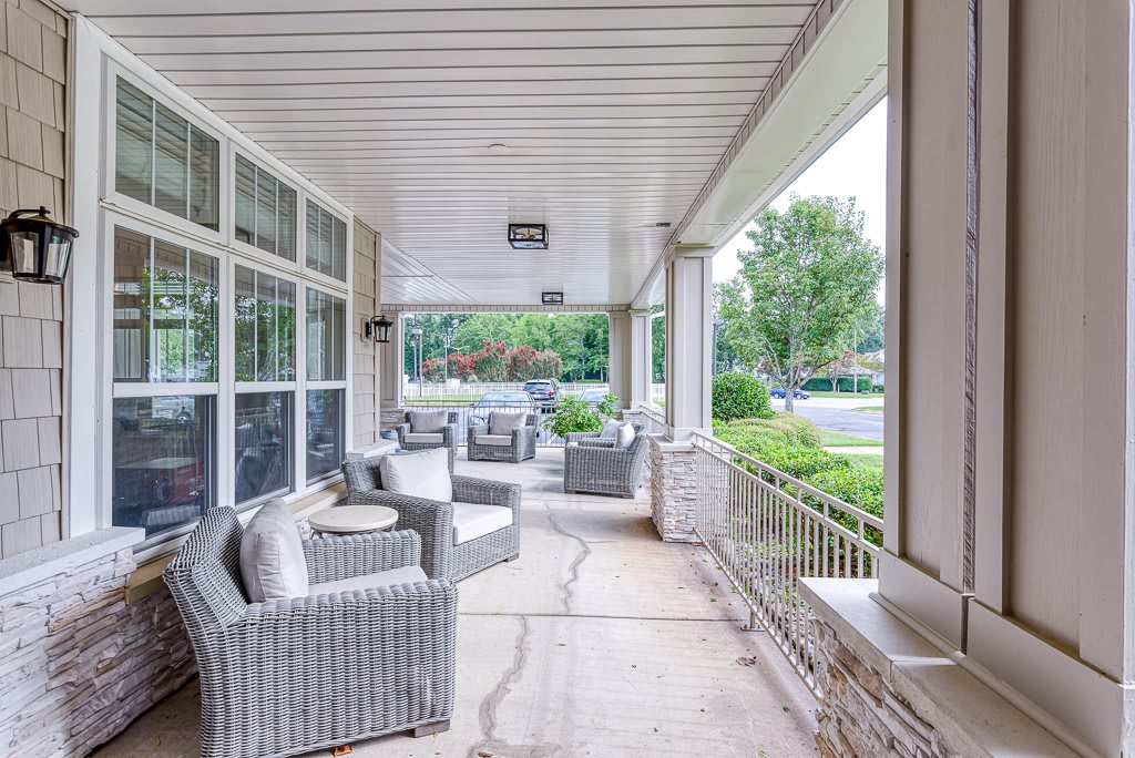 A cozy covered porch with wicker chairs and outdoor seating, ideal for relaxation.