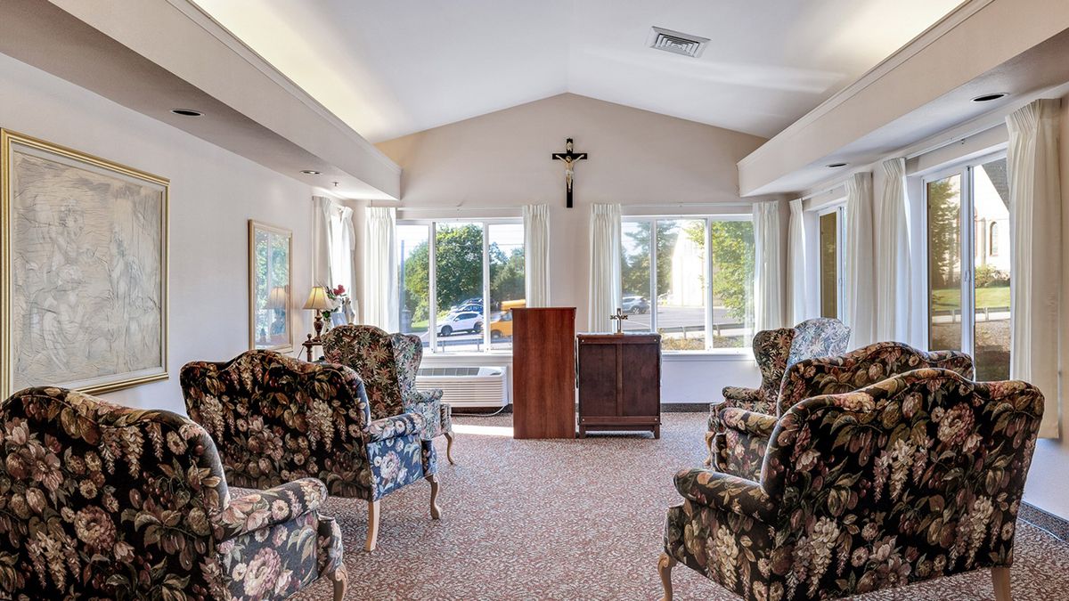 A cozy living room with patterned chairs and abundant natural light streaming through large windows.