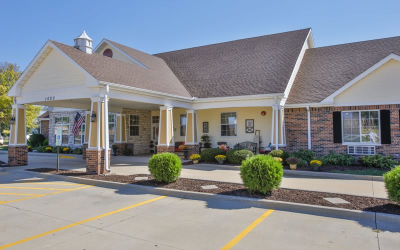 A suburban residential building with a well-maintained front yard and neatly trimmed shrubs.