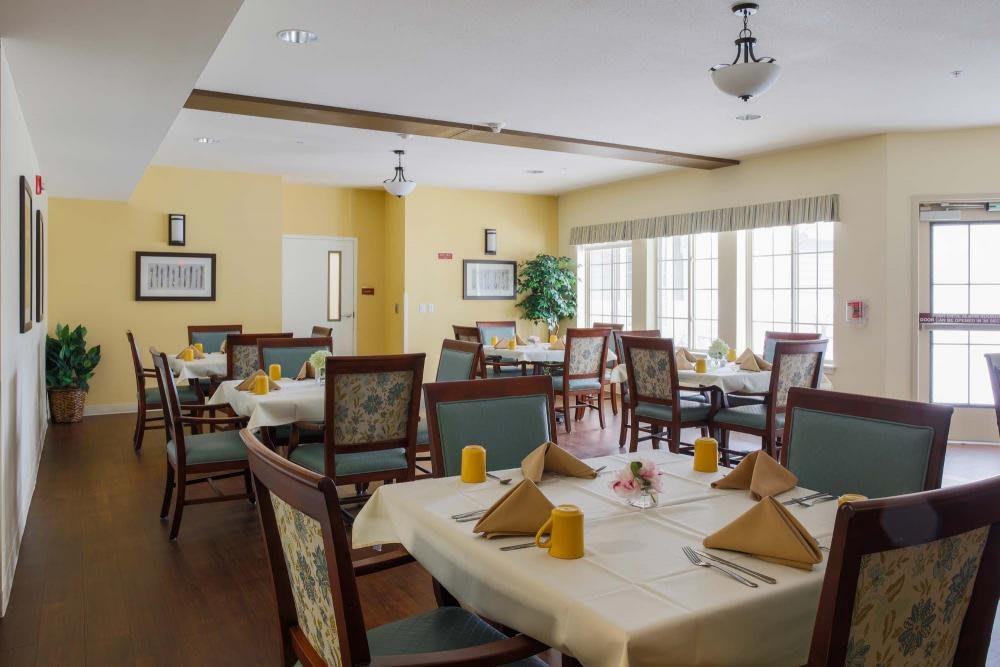 A well-lit dining room with elegantly set tables and chairs.