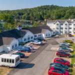Aerial view of a hotel with a parking lot surrounded by lush greenery.