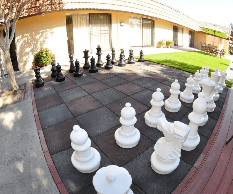 An outdoor garden with a giant chess set ready for play.