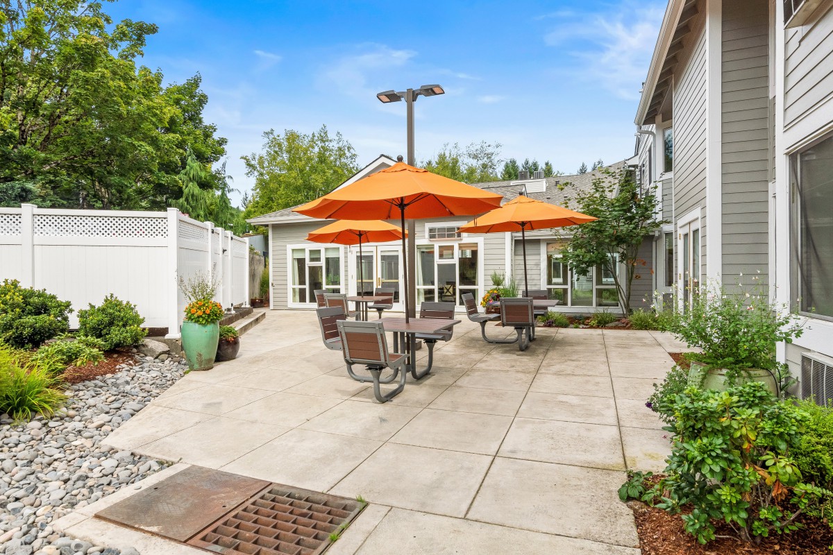 A sunny patio with orange umbrellas and outdoor seating.
