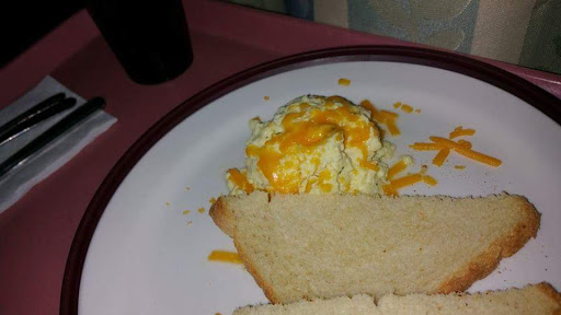 A plate featuring scrambled eggs topped with cheese and a slice of toast.