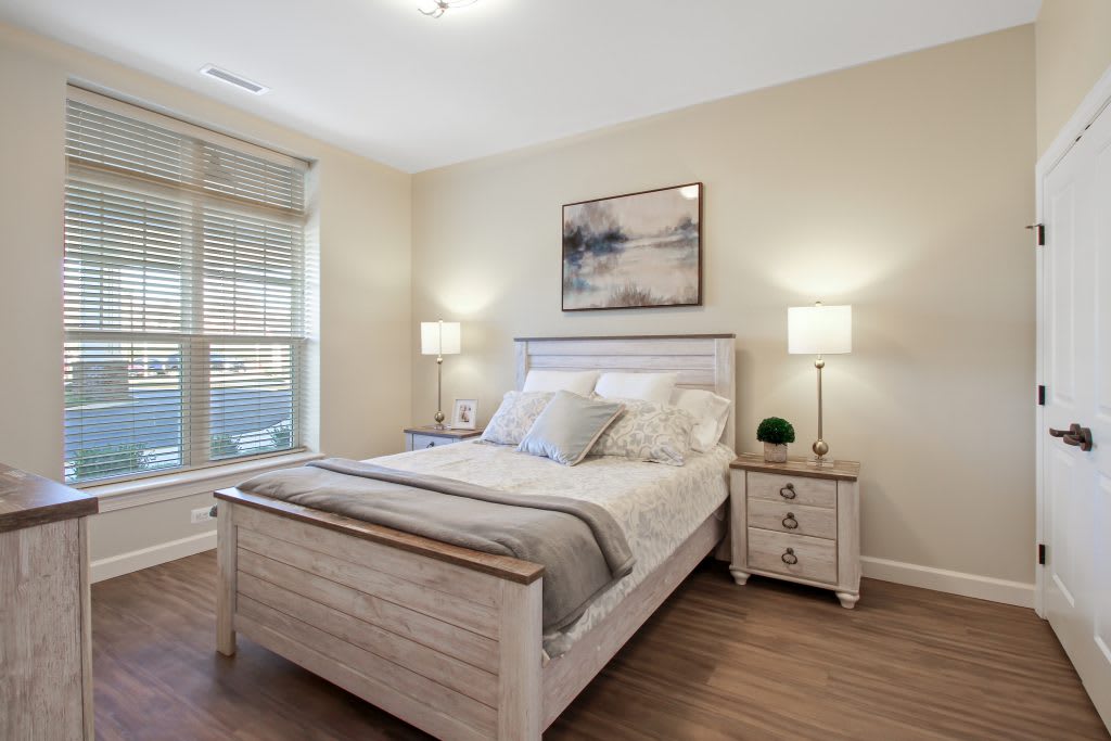 A modern bedroom with a neatly made bed, nightstands, and soft lighting.