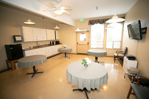 A spacious dining area with round tables and a kitchenette.