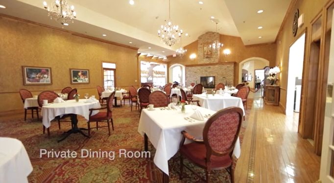 An elegant dining room with set tables and chandeliers.