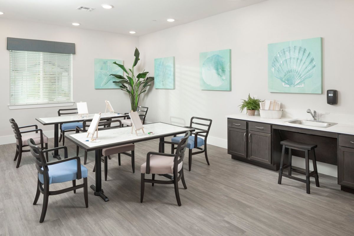 A modern office space with tables, chairs, and artwork on the walls.