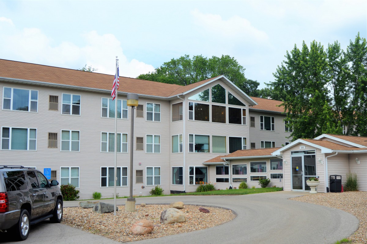 A residential apartment building with a flagpole and surrounding greenery.