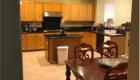 A kitchen with wooden cabinets and a central island next to a dining table.