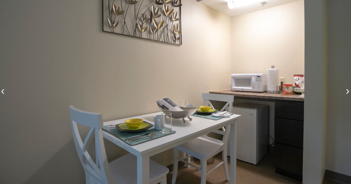 A small dining area with a set table and a microwave on the counter.