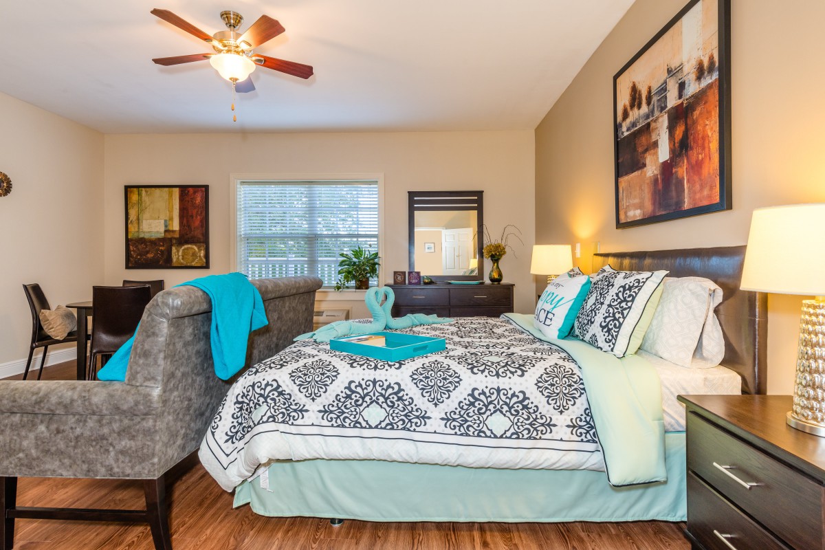 A well-decorated bedroom with a neatly made bed, featuring patterned bedding and vibrant accents.