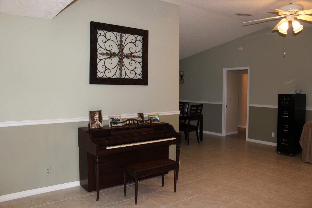 A living room with a piano and decorative wall art.