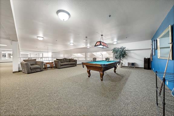 A spacious recreation room featuring a pool table and comfortable seating.