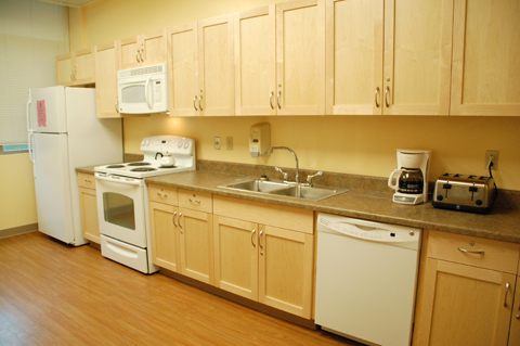 A modern kitchen featuring light wood cabinets, a countertop, and essential appliances.