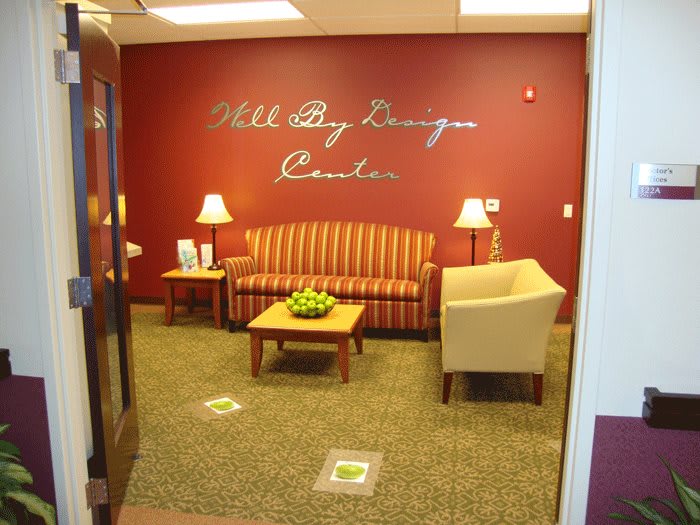 A cozy waiting area with a striped sofa, chairs, and a table against a red wall.