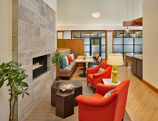 A modern and inviting living room featuring stylish orange chairs, a cozy fireplace, and contemporary furnishings.