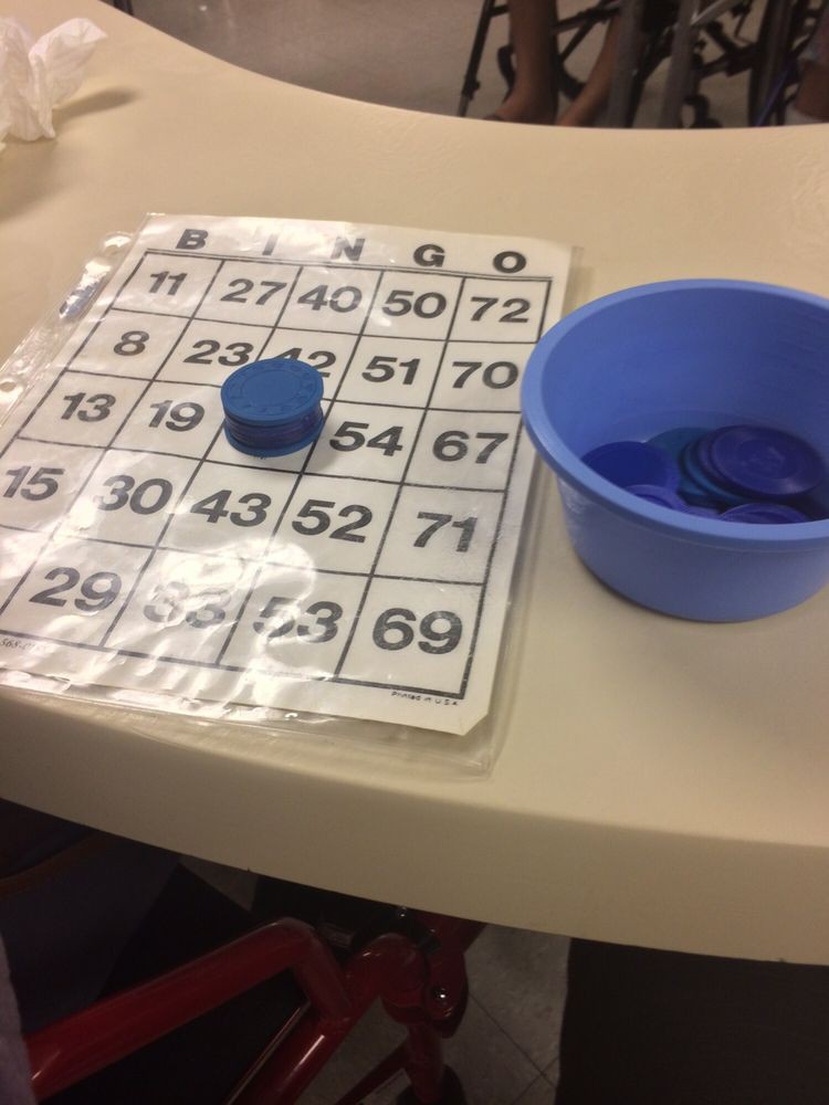 A bingo card with number tokens and a container on a table.