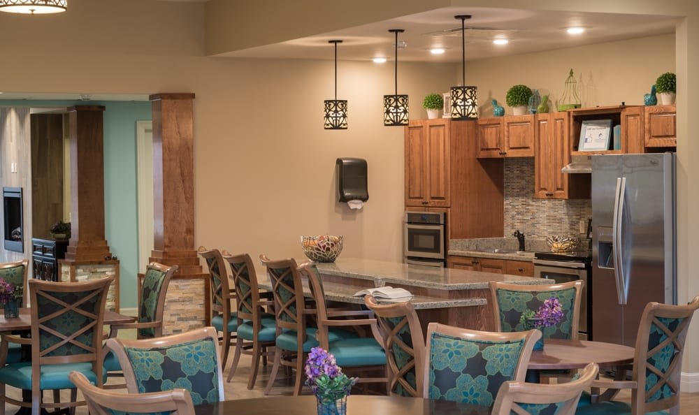 A modern kitchen and dining area featuring wooden cabinetry, pendant lighting, and comfortable seating.
