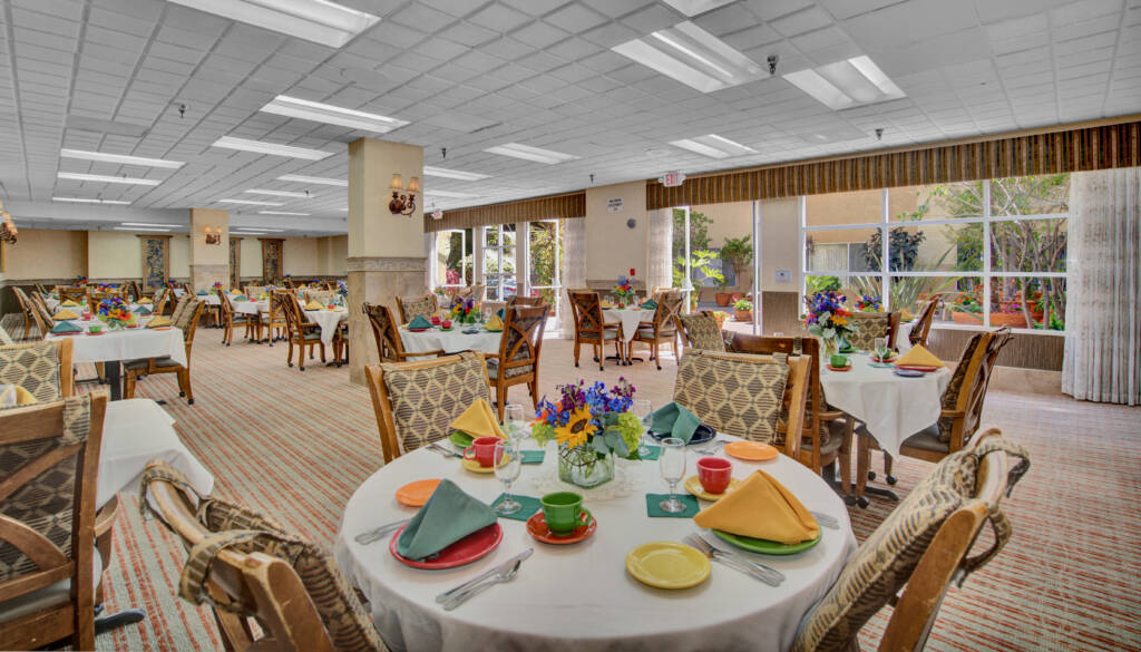 A brightly decorated dining room with colorful table settings, featuring elegant chairs and floral centerpieces.