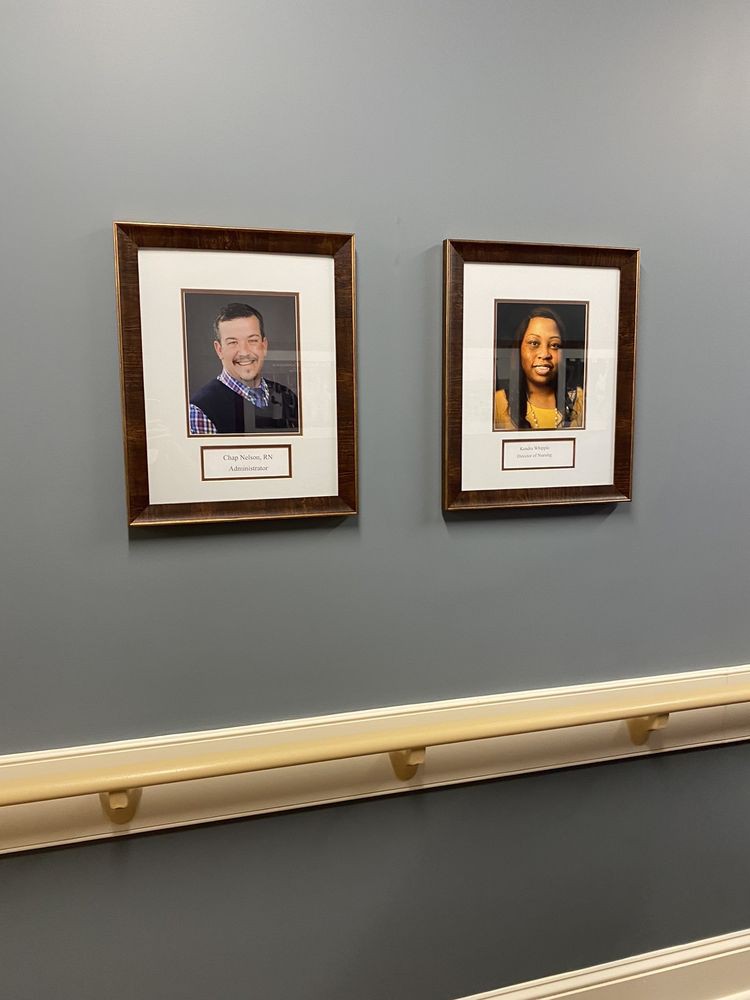 Framed portraits of two individuals displayed on a gray wall.