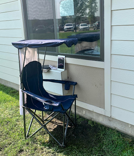 A portable chair with a canopy set up beside a window, perfect for enjoying some shade outdoors.