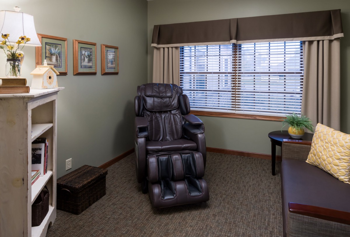 A cozy room featuring a massage chair by the window for relaxation.