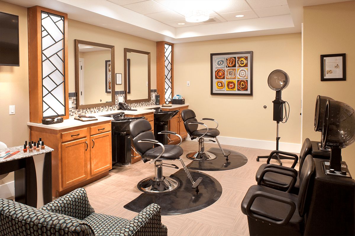An elegant beauty salon interior with styling chairs, mirrors, and a hair dryer.