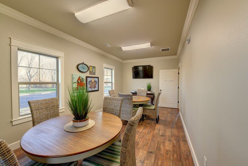 A cozy meeting room with a round table, chairs, and decorative plants.