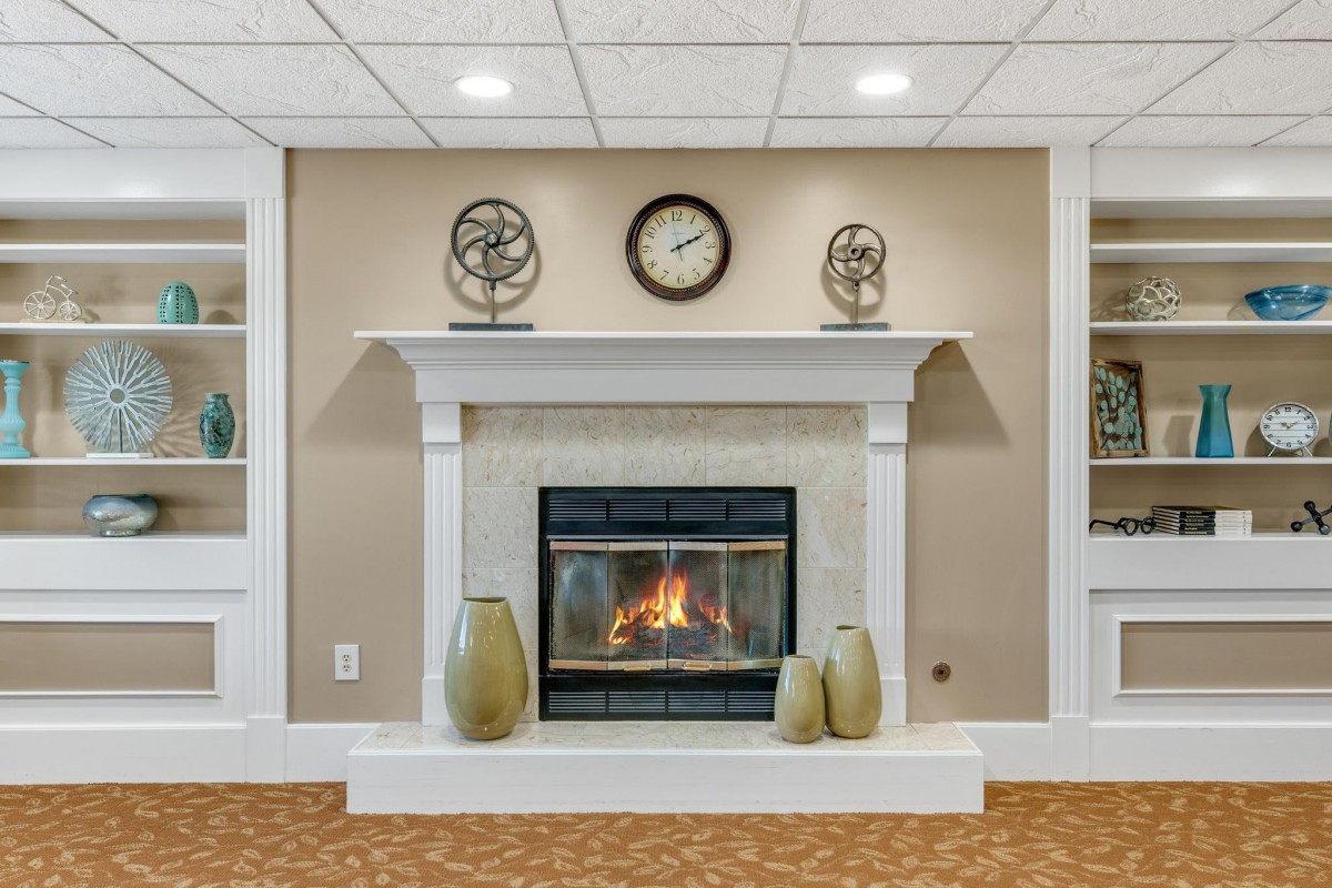 A cozy living room with a stylish fireplace, decorated with a clock and ornaments on the mantel.