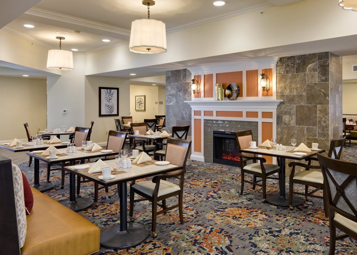 A cozy dining area with neatly arranged tables and chairs, featuring warm lighting and elegant decor.
