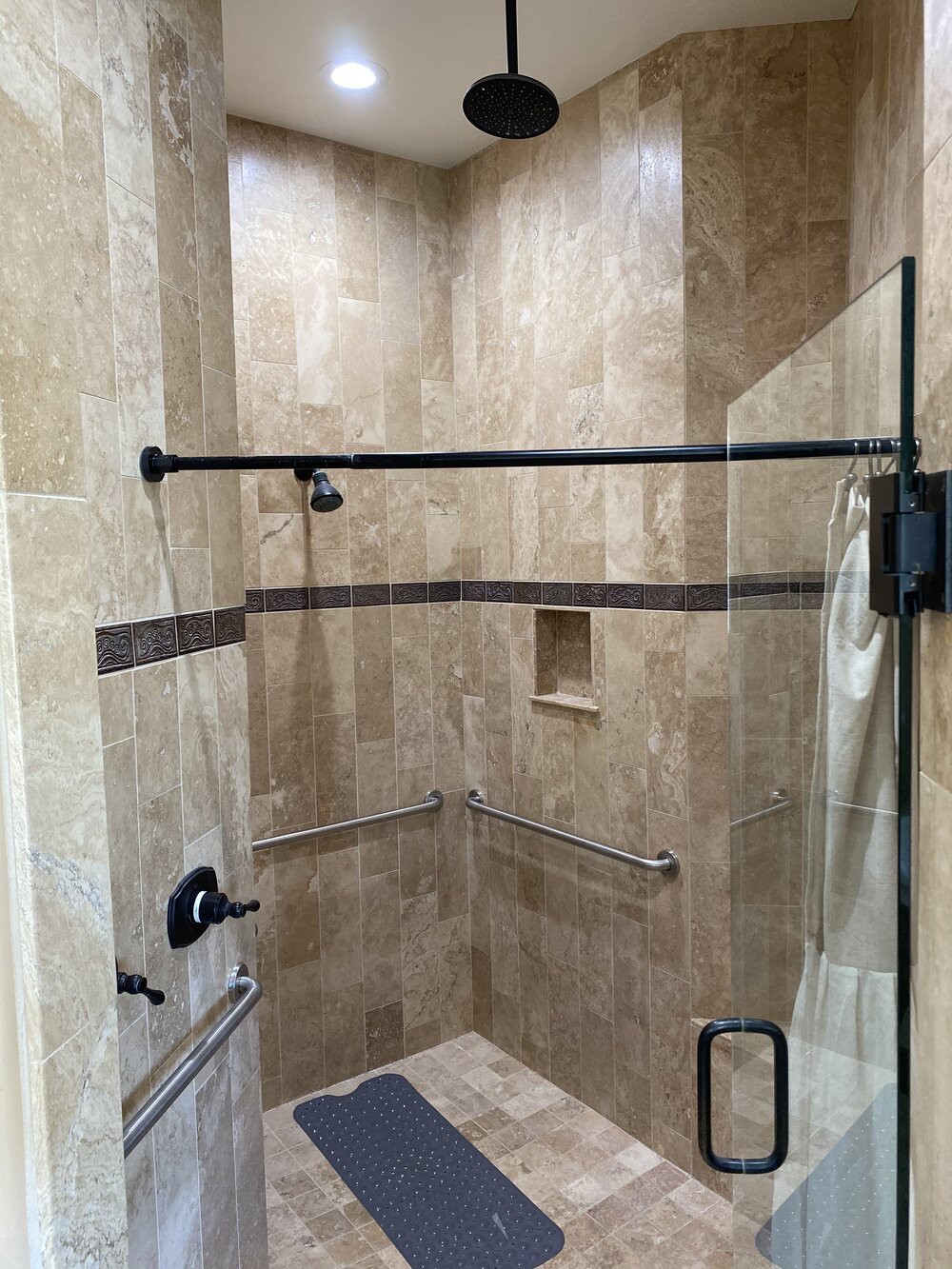 A modern shower with a glass door and tiled walls.