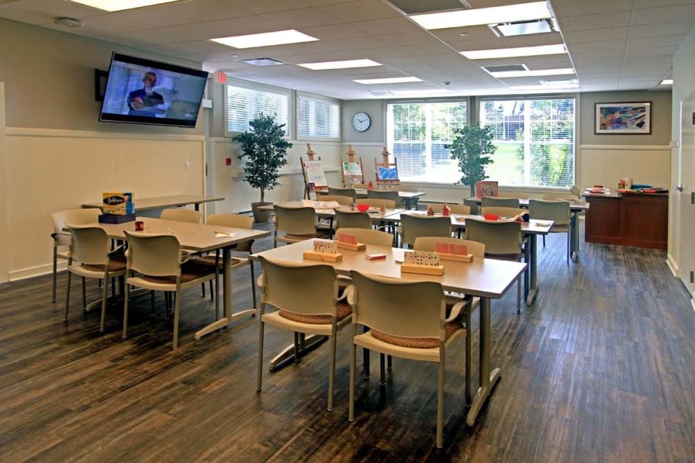 A well-lit classroom with multiple desks and chairs, featuring educational tools like a whiteboard and television.