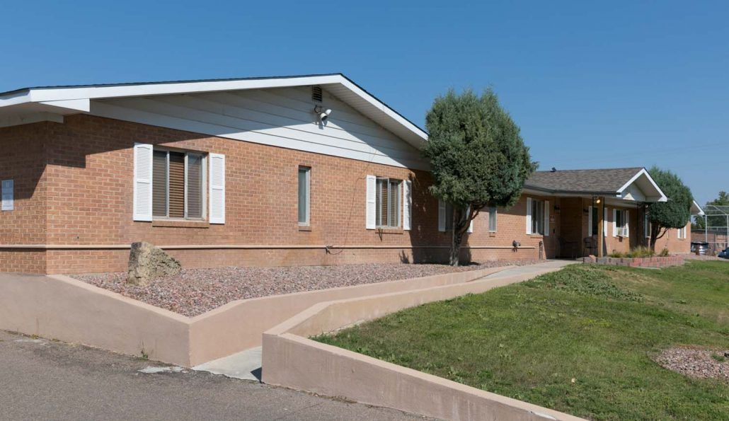 A brick residential house with a green front yard and clear blue sky.